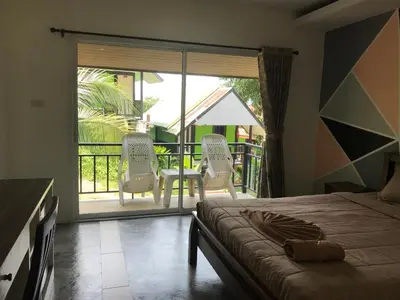 a bedroom with a bed and two chairs on a balcony at PP Midnight Hotel in Phi Phi Don