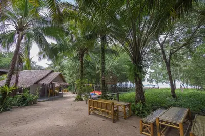a park with benches and palm trees and a building at Bananas Resort & Restaurant in Tha Lane Bay