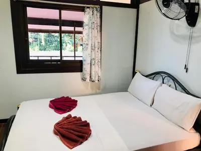 a bedroom with a bed with two red towels on it at JR GYM & Resort in Phi Phi Don
