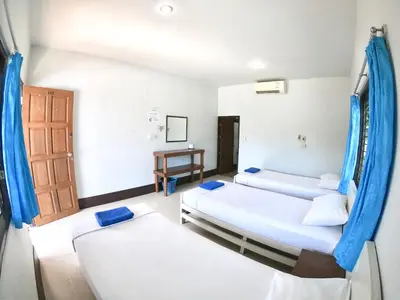 a room with two beds and a door and a table at JR GYM & Resort in Phi Phi Don