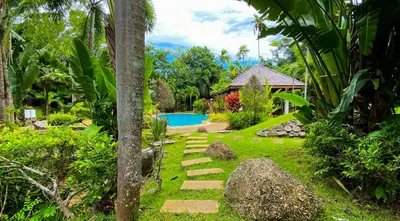 a garden with a stone path leading to a pool at Tropical garden in Phuket Town