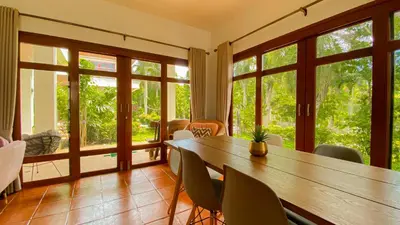 a dining room with a table and chairs and windows at Tropical garden in Phuket Town