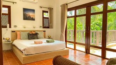 a bedroom with a bed in a room with windows at Tropical garden in Phuket Town