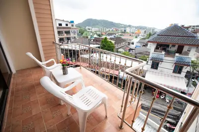 a balcony with white chairs and a table on it at Lily Holiday hotel \u767e\u5408\u5047\u65e5\u9152\u5e97 in Patong Beach