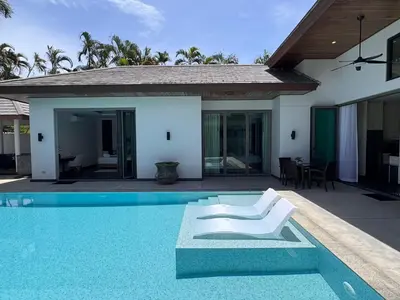 a villa with a swimming pool and a white chair at Beautiful villa walking distance from Bangtao Beach in Bang Tao Beach