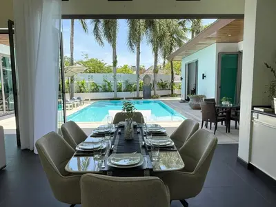 a dining room with a table and chairs and a pool at Beautiful villa walking distance from Bangtao Beach in Bang Tao Beach