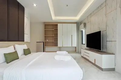 a bedroom with a large white bed with a flat screen tv at De Piraya residence in Mai Khao Beach