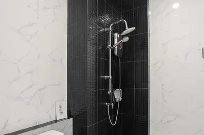 a shower with a black tiled wall and a shower at De Piraya residence in Mai Khao Beach