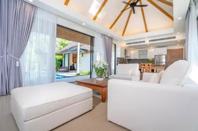a living room with white furniture and a large window at Anchan Villas Phuket - Private 2 Bedroom Pool Villas by Escape Villas in Bang Tao Beach