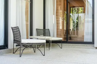 two chairs and a table in front of a building at Anchan Villas Phuket - Private 2 Bedroom Pool Villas by Escape Villas in Bang Tao Beach