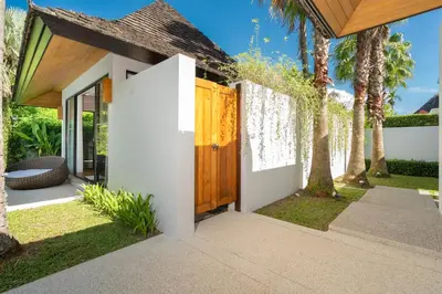 a house with a wooden gate and palm trees at Anchan Villas Phuket - Private 2 Bedroom Pool Villas by Escape Villas in Bang Tao Beach