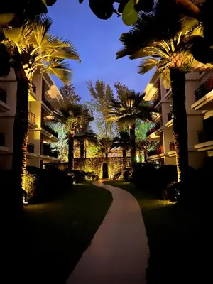 a walkway with palm trees in front of a building at The Title Rawai Beachfront (Sea paradise) in Rawai Beach