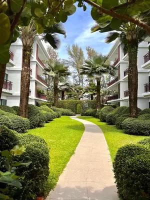 a walkway in front of a building with trees and bushes at The Title Rawai Beachfront (Sea paradise) in Rawai Beach