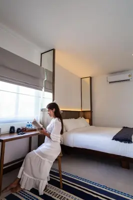 a woman reading a book in a hotel room at Baan Kamana Guest House in Phangnga