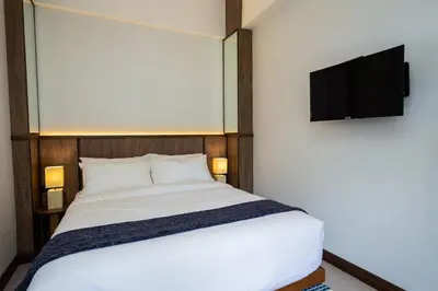 a bedroom with a bed with a television on the wall at Baan Kamana Guest House in Phangnga