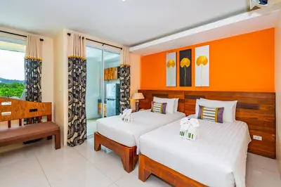 two beds in a room with orange walls at The Cheetar Hotel in Amphoe Kathu
