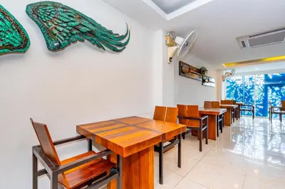 a dining room with wooden tables and chairs at The Cheetar Hotel in Amphoe Kathu