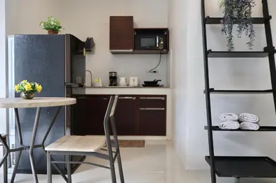 a kitchen with a table and chairs and a shelf at Chonlada Holiday Home - 2 BR Pool Access Bungalow - Kamala Beach in Kamala Beach