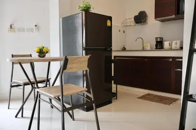 a kitchen with a refrigerator and a table and chairs at Chonlada Holiday Home - 2 BR Pool Access Bungalow - Kamala Beach in Kamala Beach