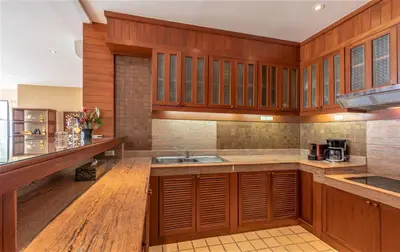 a kitchen with wooden cabinets and a sink at Beachfront Kalim Beach Villa in Patong Beach