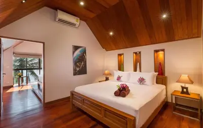a bedroom with a large white bed with flowers on it at Beachfront Kalim Beach Villa in Patong Beach
