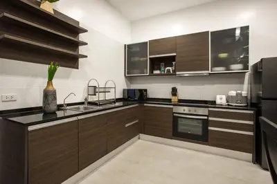 a kitchen with wooden cabinets and a black refrigerator at Villa Elima. Lovely pool villa 2 bedrooms at Rawai in Rawai Beach