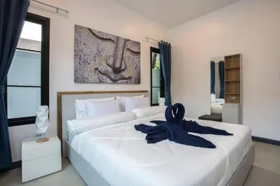 a large white bed with a blue robe on it at Villa Elima. Lovely pool villa 2 bedrooms at Rawai in Rawai Beach