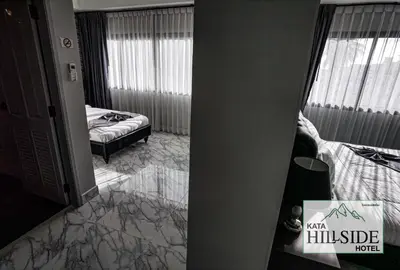 a bedroom with a bed and a hallway with a mirror at Kata Hillside Hotel in Kata Beach