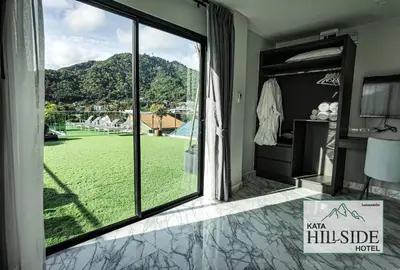 a room with a large window with a view of a yard at Kata Hillside Hotel in Kata Beach