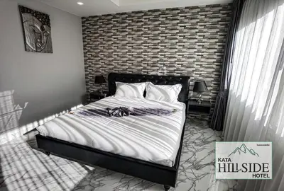 a bedroom with a bed and a brick wall at Kata Hillside Hotel in Kata Beach