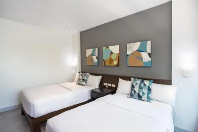 two beds in a hotel room with paintings on the wall at Happy Apartment on Karon Beach in Karon Beach
