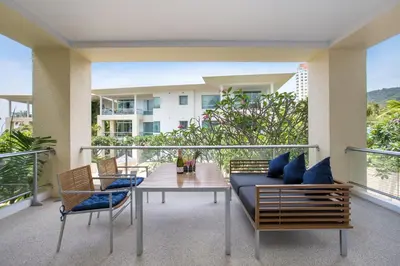 a balcony with a couch and chairs on a balcony at Happy Apartment on Karon Beach in Karon Beach