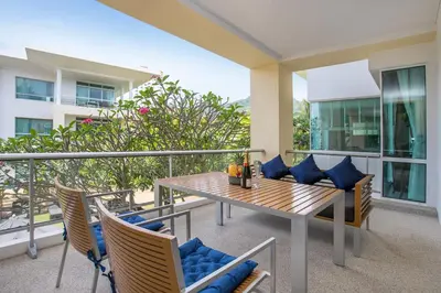 a balcony with a wooden table and chairs on a balcony at Happy Apartment on Karon Beach in Karon Beach