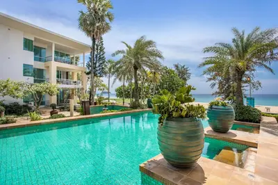 a pool at a resort with palm trees and a building at Happy Apartment on Karon Beach in Karon Beach