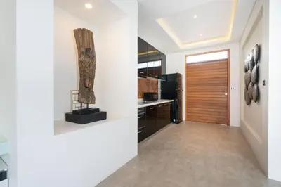 a kitchen with white walls and a wooden door at Eden Escape Naiyang Beach in Phuket Town