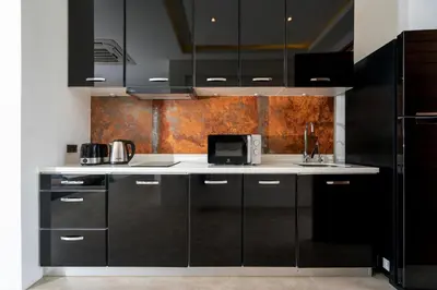 a kitchen with black cabinets and a microwave at Eden Escape Naiyang Beach in Phuket Town