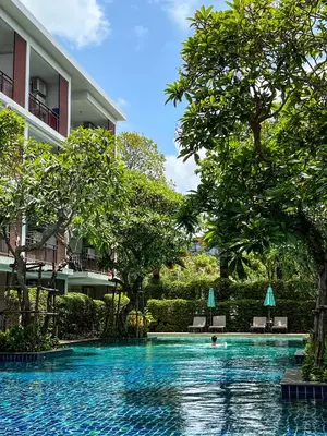 a person swimming in a swimming pool next to a building at The Title Rawai: Beachfront condotel in Rawai Beach