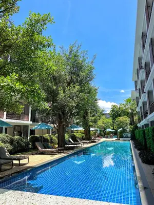 a swimming pool with chairs and umbrellas next to a building at The Title Rawai: Beachfront condotel in Rawai Beach