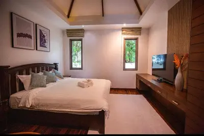 a bedroom with a bed and a tv and windows at Poly Villa Naya 3 in Rawai Beach