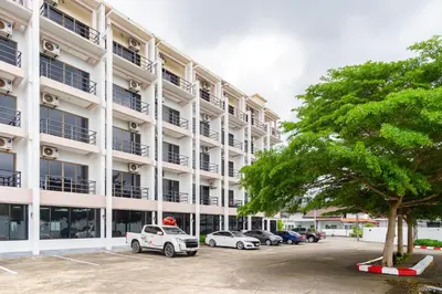 a large white building with cars parked in a parking lot at Goodday Kathu in Kathu