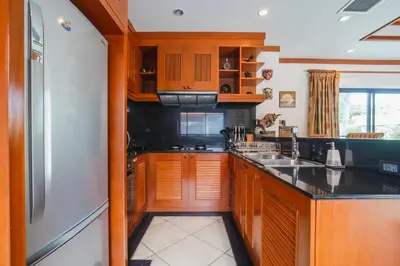a kitchen with wooden cabinets and a black counter top at Lotus Pool Villa Your Own Slice Of Island Paradise in Rawai Beach