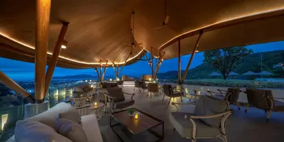 a restaurant with a roof with chairs and tables at Noku Phuket in Chalong