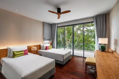 a hotel room with two beds and a window at Noku Phuket in Chalong