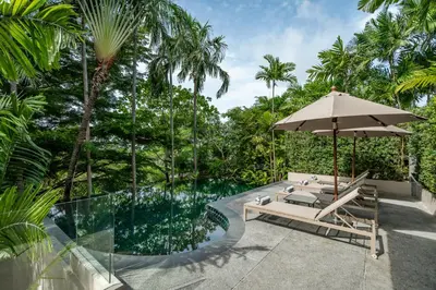 a patio with a table and an umbrella next to a pool at Noku Phuket in Chalong