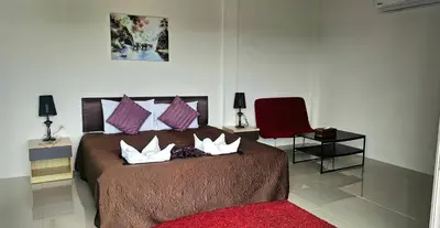 a bedroom with a bed with pillows and a red chair at AM Surin Place in Surin Beach