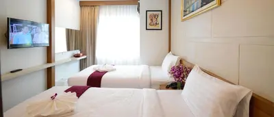 a hotel room with two beds and a tv at The Patong Center Hotel in Patong Beach