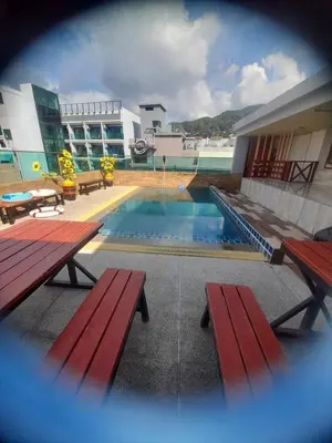 a swimming pool with two benches and a building at The Patong Center Hotel in Patong Beach