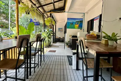 a restaurant with wooden tables and chairs and plants at Sweed Dee Hostel in Phi Phi Don