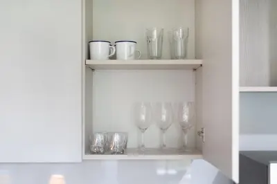a row of wine glasses on a shelf in a kitchen at Tropical Living Surin Beach Phuket in Surin Beach