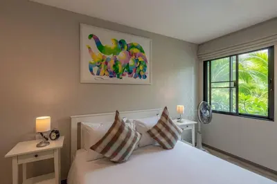 a bedroom with a bed with two tables and a window at Title Naiyang residence Excellent location with pool view in Nai Yang Beach